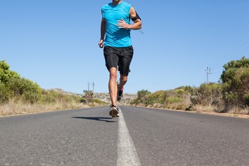 Athletic man jogging on open road