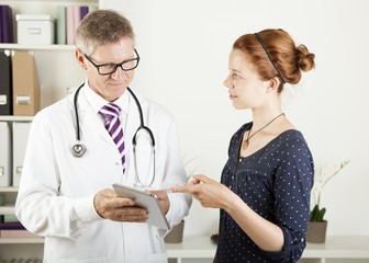 doctor and a patient woman showing something on tablet pc