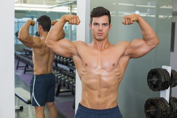 Shirtless muscular man flexing muscles in gym