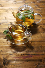 Composition of fresh mint tea in glass cup and teapot