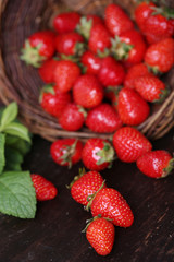 Ripe sweet strawberries in wicker basket on wooden background