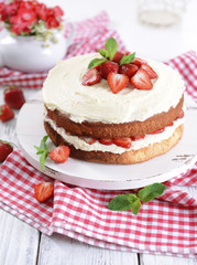 Delicious biscuit cake with strawberries on table close-up