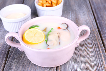 Tasty soup with oysters on wooden table