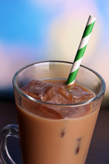 Glass of iced milk coffee on bright background
