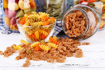 Colorful pasta in glass jars on wooden background