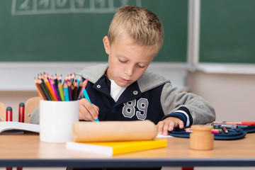 junge in der schule malt mit buntstiften