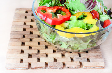 Bowl of salad and teak plate mat close-up