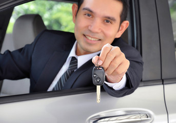 Asian businessman showing a car key - car sale & rental concept