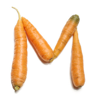 Alphabet letter M arranged from fresh carrots isolated
