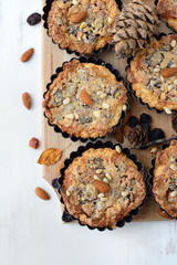 Tarts with nuts and raisins filling on a wooden board.