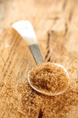 Brown sugar in spoon on rustic wooden table.