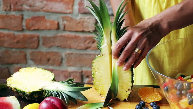 Woman cutting pineapple on the chopping board, closeup