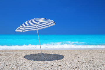 Sun umbrella on a pebble beach with turquoise sea and sky