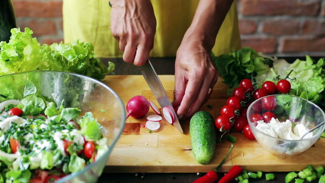 Woman cutting radish on the chopping board, closeup