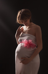 Pregnant woman on the dark background