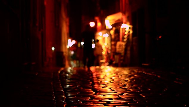 People walking on dark street at night.