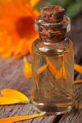 Calendula extract in a glass bottle and flowers vertical