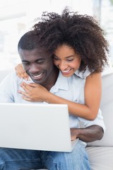 Obraz na płótnie Canvas Attractive couple using laptop together on sofa