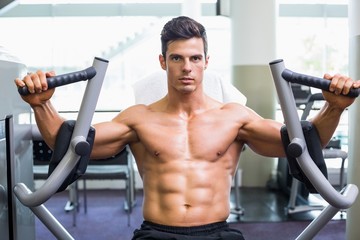 Fototapeta na wymiar Muscular man working on fitness machine at the gym