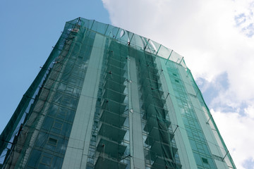 building under construction wrapped in a green net for safety