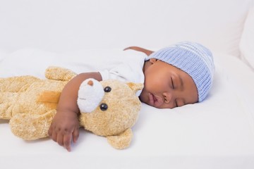 Adorable baby boy sleeping peacefully with teddy