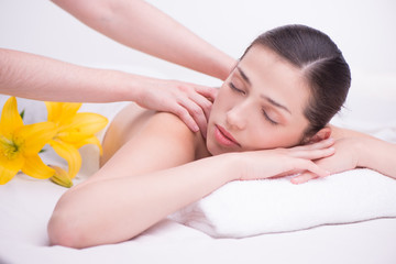 Fototapeta na wymiar Relaxed woman with flowers in spa center enjoying massage