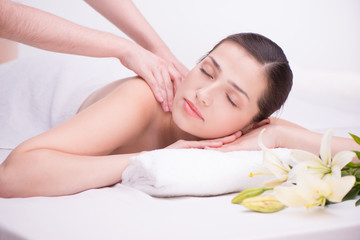 Fototapeta na wymiar Relaxed woman with flowers in spa center enjoying massage