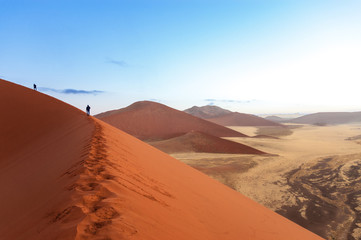 Fototapeta na wymiar People on sunrise dunes of Namib desert, South Africa