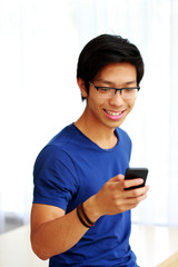 Happy asian man using smartphone at home