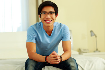 Obraz premium Happy asian man sitting on the bed at home