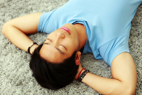 Young asian man sleeping on the carpet at home