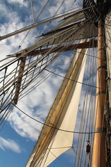 Tall ship mast and sail against blue sky