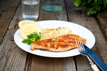 Grilled salmon with potatoes on a white plate\