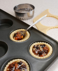 Using teaspoon to fill pastry cases with mincemeat