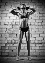Muscular woman on brick wall (monochrome version)