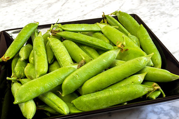 Pods of peas on a black plate