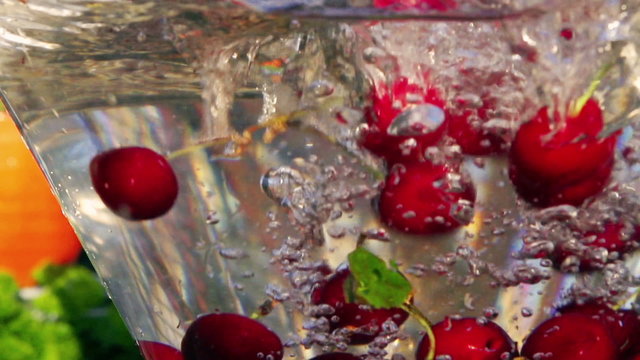 Cherry falling into glass of water, closeup, slow motion shot 