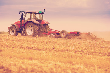 Obraz premium Tractor cultivating wheat stubble field, crop residue.