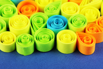 Colorful quilling on blue background close-up
