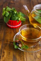 Composition of fresh mint tea in glass cup and teapot
