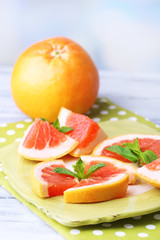 Fototapeta na wymiar Ripe grapefruits on plate, on wooden table, on light background