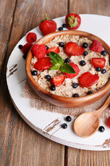 Tasty oatmeal with berries on table close-up