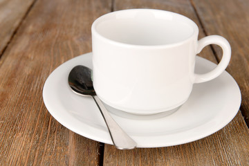 Empty cup with tea spoon on wooden background