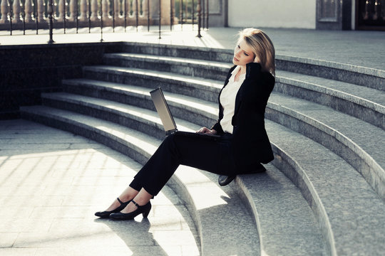 Young business woman using laptop on the steps
