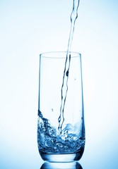 water pouring into glass on blue background
