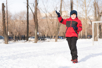 Fototapeta na wymiar boy in winter park throwing a snowball