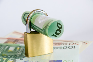 Euro Geldschein gerollt mit Vorhaengeschloss auf Geldscheinen