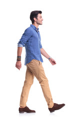 side view of a smiling young casual man walking