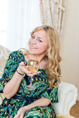 Beautiful  woman sitting on an armchair and having a glass of wi