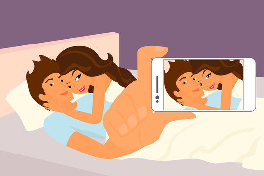 Happy couple taking a snapshot of themselves in bed